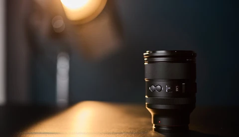 Camera lens on textured surface with warm bokeh lighting in background.