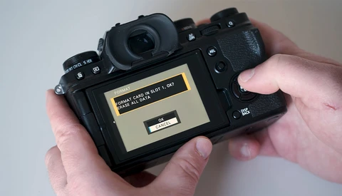 Photographer's hands holding a mirrorless camera displaying a memory card error message on the rear LCD screen.