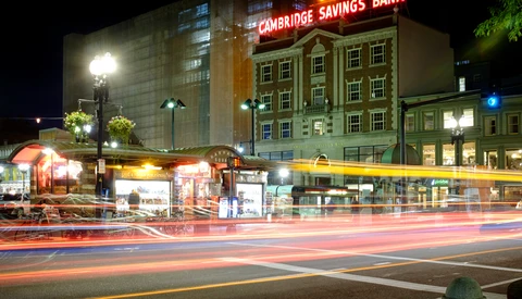 Night street scene with light trails from passing vehicles and illuminated historic buildings.