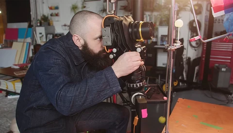 Photographer operating a large format camera mounted on a tripod in a studio setting.