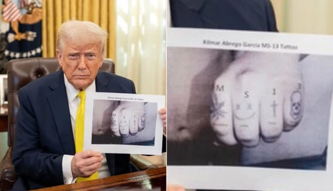 Man in business suit holding up photographs of tattooed knuckles with letters.