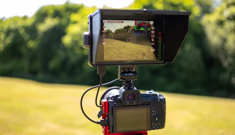 External monitor mounted on DSLR camera showing live video feed with exposure information overlay and histogram display.