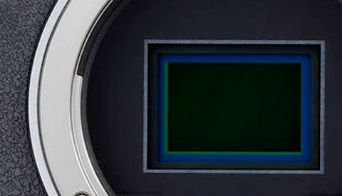 Camera sensor with blue and green color filter array pattern visible through open aperture.