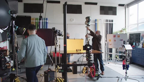 Professional film or photo production studio with crew operating camera equipment and lighting rigs during an active shoot.