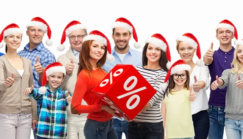 Group of diverse people wearing Santa hats holding a red discount sign with percentage symbols.