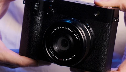 Fujifilm X-Pro1 camera with Fujinon Aspherical lens held in hands during product demonstration.