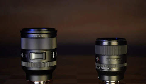 Two camera lenses of different sizes displayed side by side against a dark brown background.
