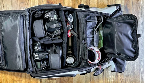 Professional camera backpack with organized gear compartments containing cameras, lenses, and photography accessories.