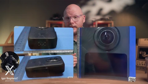 Tech reviewer comparing two compact camera models displayed on blue foam board against studio backdrop.
