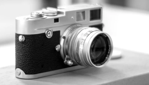 Vintage rangefinder camera with black leather grip and chrome top plate, fitted with a standard prime lens.