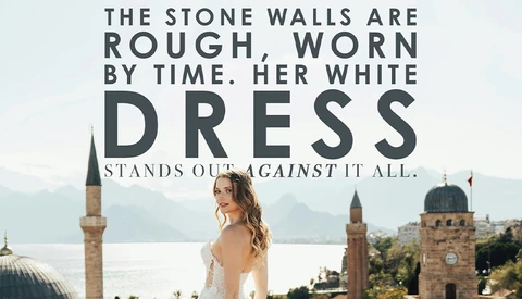 Bride in white dress photographed from behind against waterfront cityscape with historic mosques and minarets.