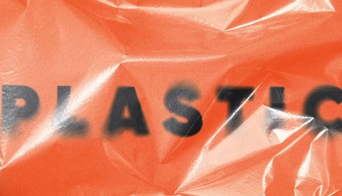 Plastic-wrapped orange surface with partial black text reading "PLAST" visible through the wrinkles and folds.