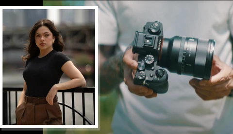 Portrait of a woman in black top and brown skirt standing against an urban railing; detail of hands holding a mirrorless camera with telephoto lens.