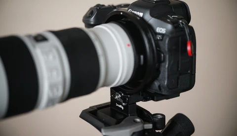 Canon EOS R5 mirrorless camera mounted on tripod with white telephoto lens attached.
