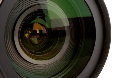 Close-up of a wide-angle camera lens with green coatings and golden reflections in the front element.