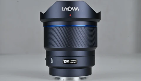 Laowa 12mm f/2.8 ultra-wide angle lens with black barrel and blue accent ring, shown in product display orientation.
