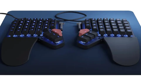 Ergonomic split mechanical keyboard with illuminated keys and matching mouse on dark mousepad.