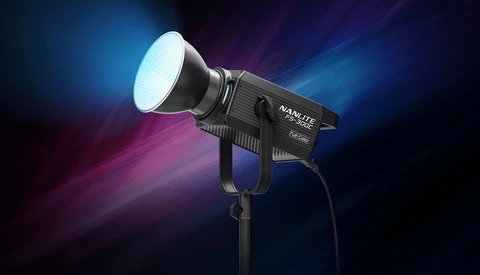 Professional LED spotlight with white beam output against a dark background with blue and magenta light rays.