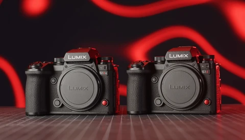 Two Panasonic Lumix mirrorless cameras positioned side-by-side against a dark background with red neon lighting.