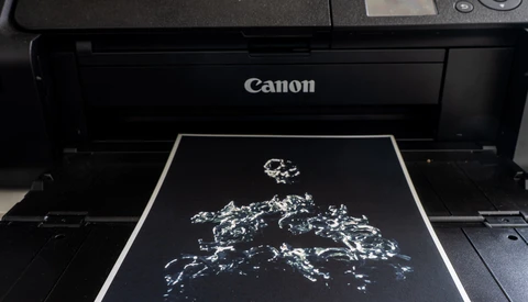 Canon printer with a high-contrast black and white map of Europe printing on glossy paper.