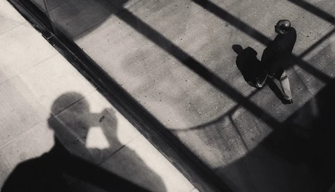 Overhead view of a person's shadow cast on concrete steps in strong sunlight.