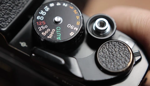 Close-up of vintage camera's top plate showing aperture dial with f-stops and shutter speed settings.