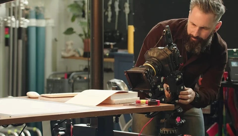 Filmmaker adjusting a cinema camera mounted on a slider in a studio workspace.