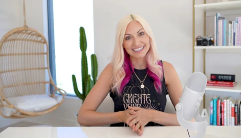 Woman with platinum blonde hair and pink underlights smiling at camera in bright studio setting.