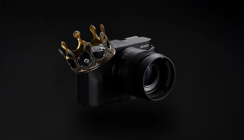 Sony mirrorless camera with ornate gold crown prop on black background.
