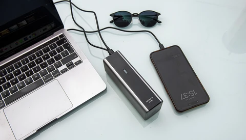 Laptop, two portable power banks, and sunglasses arranged on a white surface.