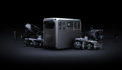 Portable power station surrounded by professional drones and cameras against a dark background.