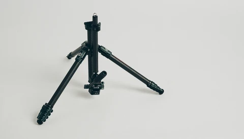 Black tripod with extended legs and center column against white background.