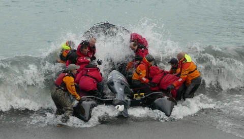 Rescue team in inflatable boat navigating through ocean waves during active water conditions.
