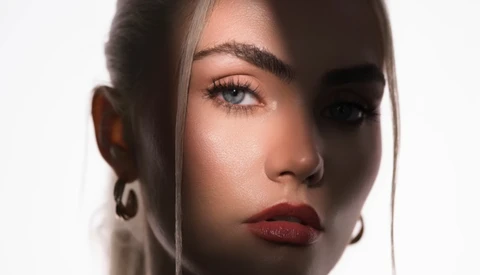 Portrait of a woman with dramatic side lighting creating a split-face effect with deep shadows.