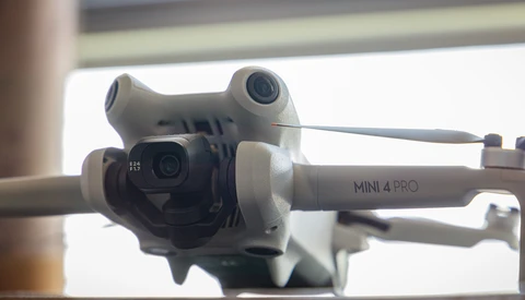 DJI Mini 4 Pro drone with camera gimbal and dual vision sensors mounted on arm.