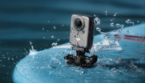 Action camera mounted on a blue surface with water splashing around it during a water sports activity.