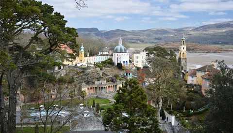 Hilltop monastery with white dome and bell tower overlooking a river valley and mountains.