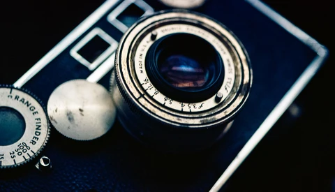 Vintage rangefinder camera with blue body and chrome lens barrel, shot from above against dark background.