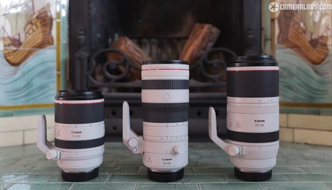 Three Canon RF-mount telephoto lenses with white grip rings displayed side by side on a decorative surface.