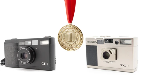 Two vintage compact cameras flanking a gold first-place medal with red ribbon.