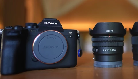 Sony α7 mirrorless camera body and Sony E-mount zoom lens displayed on wooden surface with warm studio lighting.