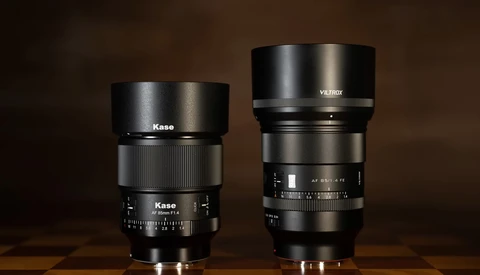 Two manual focus prime lenses side by side on a wooden surface against a brown background.