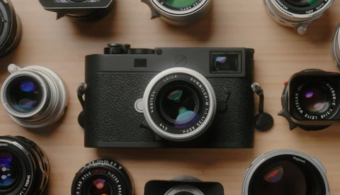 Rangefinder camera with interchangeable lenses arranged on wooden surface.