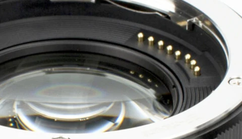 Close-up of camera lens mount showing gold electrical contacts and black metal bayonet ring.