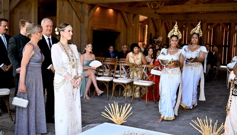 Formal event with guests in traditional Thai dress and Western formal wear in ornate wooden hall.