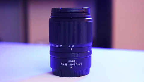 Nikon DX 18-140mm f/3.5-6.3 zoom lens with focus and zoom rings visible against purple and pink studio lighting.