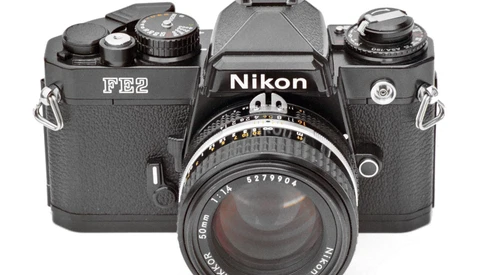 Nikon FE2 film camera with standard 50mm lens mounted, shot from front against white background.