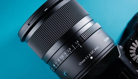 Telephoto zoom lens with focal length markings visible against a bright blue background.