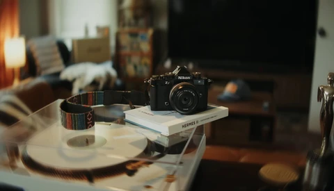 Nikon camera displayed on stacked books atop a round table in a creative workspace.
