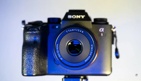 Three vintage and modern cameras arranged in a row against a light background, with a blue Startisan camera in sharp focus in the foreground.